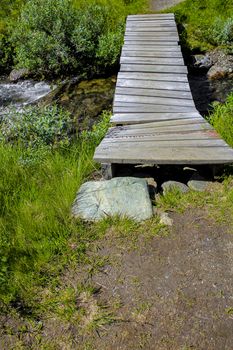 Small wooden bridge and footpath over river of Vavatn lake in Hemsedal, Norway.