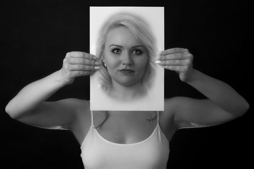 young woman holding a paper in front of face