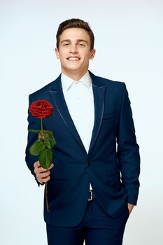 A man in a suit with a rose in his hands a gift date light background. High quality photo