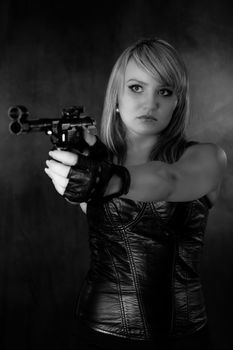 Young blonde woman in leather and with a gun