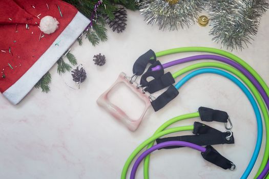 Set of expanders and Christmas decorations on a light background. Greeting card with the concept of a healthy lifestyle. Sports and fitness. Top view with space to copy. Flat lay.