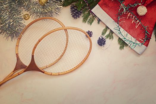 Badminton rackets and Christmas decorations on a light background. Greeting card with the concept of a healthy lifestyle. Top view with copy space. Flat lay