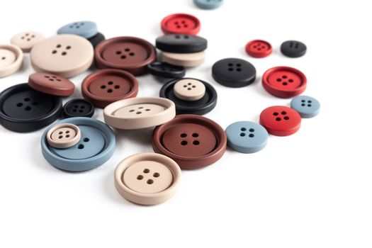 Pile of color brown, beige, grey, red, black plastic matte buttons on white, beautiful needlework, minimalism. Use for sewing. Space for text.