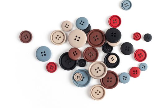 Pile of color brown, beige, grey, red, black plastic matte buttons on white, beautiful needlework, minimalism. Use for sewing. Space for text.