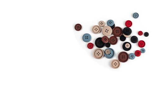 Pile of color brown, beige, grey, red, black plastic matte buttons on white, beautiful needlework, minimalism. Use for sewing. Space for text.