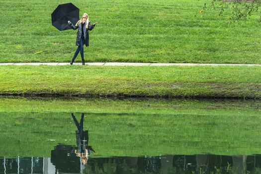 A gorgeous blonde model poses outdoors in her fall clothes while walking in a park