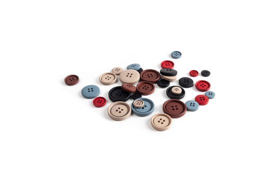 Pile of color brown, beige, grey, red, black plastic matte buttons on white, beautiful needlework, minimalism. Use for sewing. Space for text.