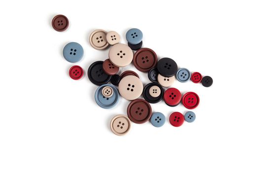 Pile of color brown, beige, grey, red, black plastic matte buttons on white, beautiful needlework, minimalism. Use for sewing. Space for text.