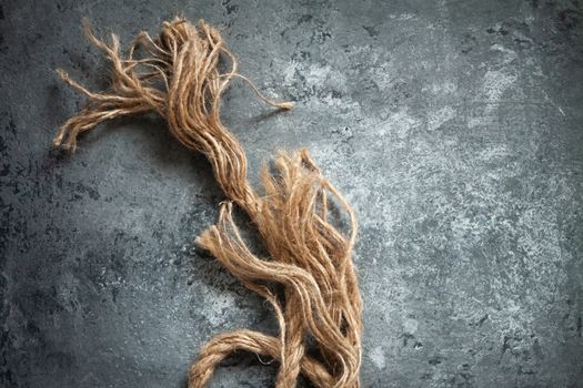 large battered jute rope on a gray abstract concrete background. Space for text.