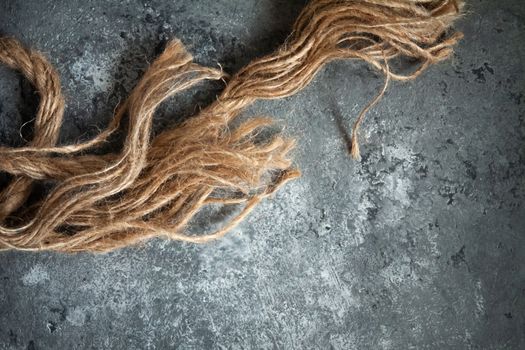 large battered jute rope on a gray abstract concrete background. Space for text.