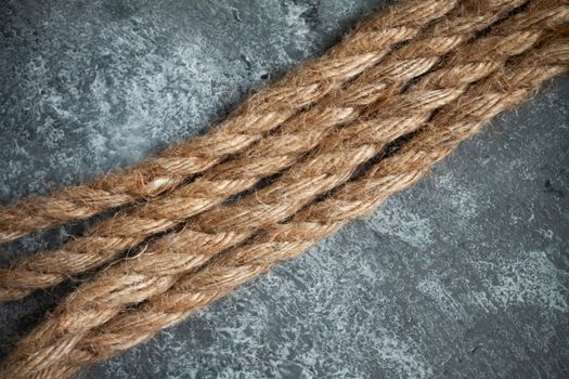 large battered jute rope on a gray abstract concrete background. Space for text.