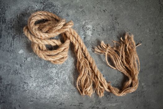 large battered jute rope on a gray abstract concrete background. Space for text.