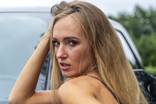 A gorgeous blonde model poses with a black truck on a fall day