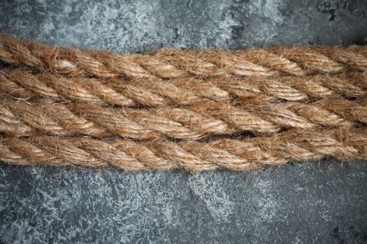 large battered jute rope on a gray abstract concrete background. Space for text.