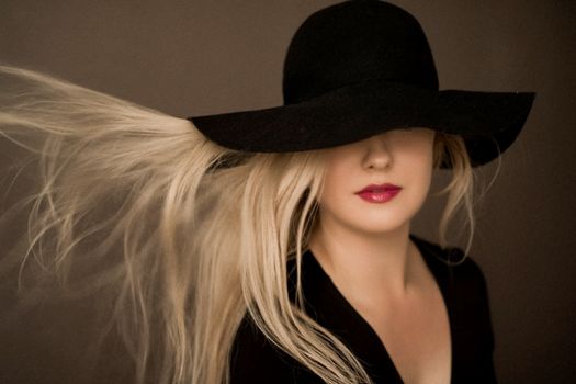 Classy blonde woman wearing a hat, artistic film portrait for fashion campaign and beauty brand design