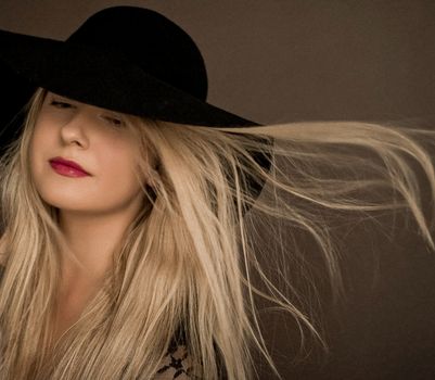 Classy blonde woman wearing a hat, artistic film portrait for fashion campaign and beauty brand design