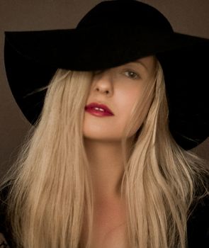 Classy blonde woman wearing a hat, artistic film portrait for fashion campaign and beauty brand design