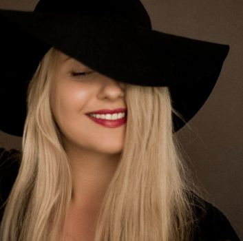 Classy blonde woman wearing a hat, artistic film portrait for fashion campaign and beauty brand design