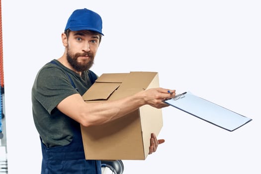 Working male courier with box in hand documents delivery service light background. High quality photo