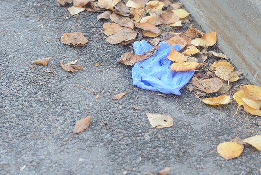 Crumpled medical gloves lie on the ground in a pile of autumn leaves.Plastic pollution caused by Covid 19