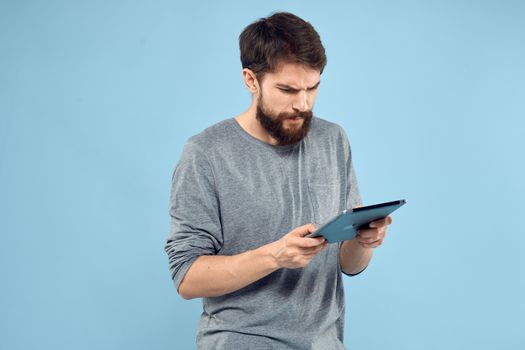 Emotional man with a tablet in the hands of a wireless device internet technology lifestyle blue background. High quality photo