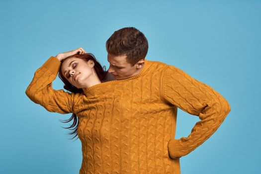 couple in yellow sweater posing against blue background cropped view. High quality photo