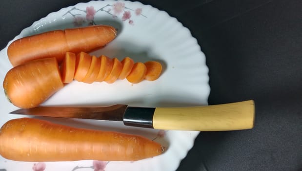Fresh and delicious and healthy carrot pieces and a knife on plate