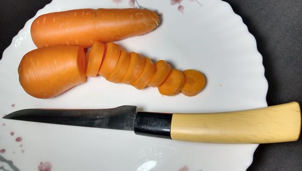 Fresh and delicious and healthy carrot pieces and a knife on plate