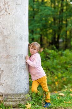 .A girl with a broken arm stands near a column in an old park on an autumn walk