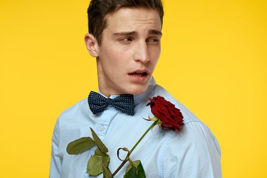 Portrait of a man with a red rose on a yellow background and a light shirt bow tie gentleman. High quality photo