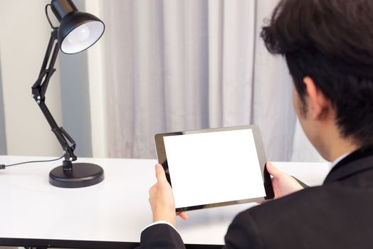 Work from home, Back view of Asian young businessman smile wearing suit video conference call or facetime by smart digital tablet computer blank screen on desk