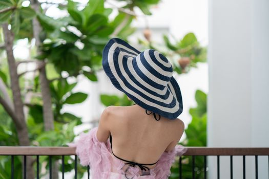 woman in black bikini swimwear covering face with hat.