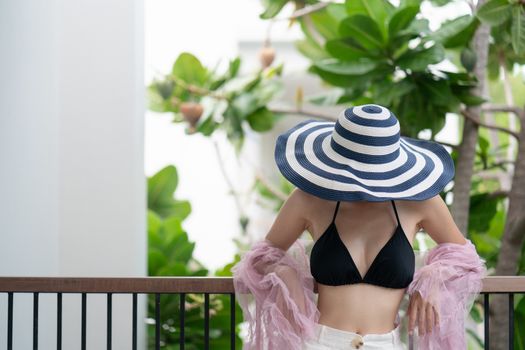 woman in black bikini swimwear covering face with hat.