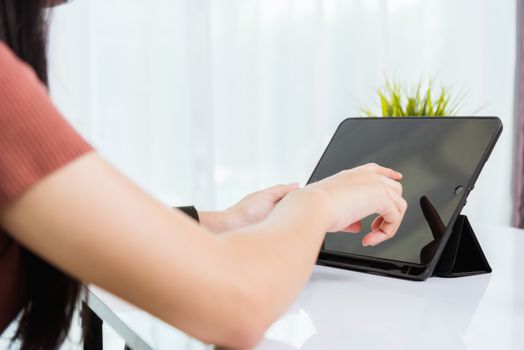 Work from home, Asian young businesswoman wearing face mas protactive video conference call or facetime touch digital smart tablet computer she meeting with colleagues on desk, situation coronavirus