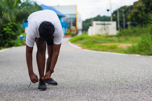 Close up Asian sport runner black man standing he trying shoelace running shoes getting ready for jogging and run at the outdoor street health park, healthy exercise workout concept