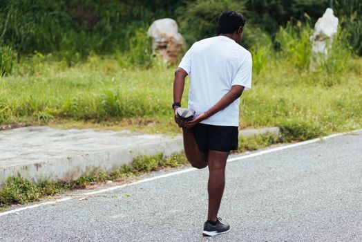 Close up Asian young athlete sport runner black man wear watch lift feet stretching legs and knee before running at the outdoor street health park, healthy exercise before workout concept