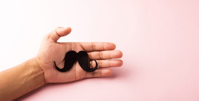 The man uses hand holding black mustache, studio shot isolated on white background, Prostate cancer awareness month, Fathers day, minimal November moustache concept