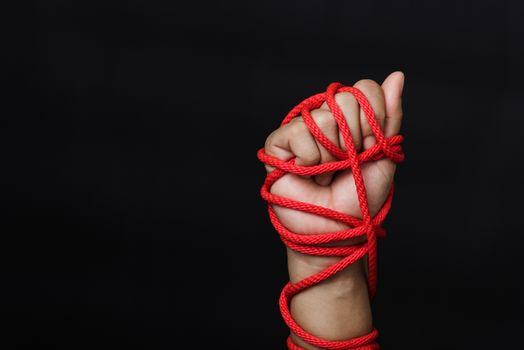 Woman hand tied up with rope on black background, Human trafficking and abuse, International Human Rights day