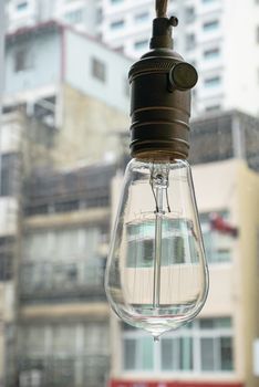 The close up of vintage light bulb aesthetic hanging with downtown background.