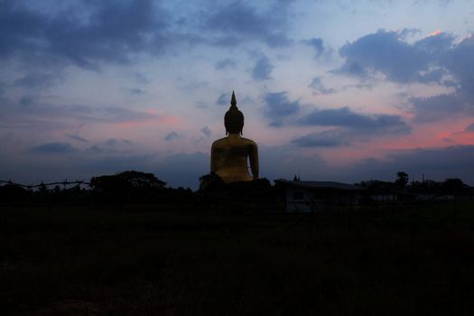 Buddha with silhouette at the blue sky.