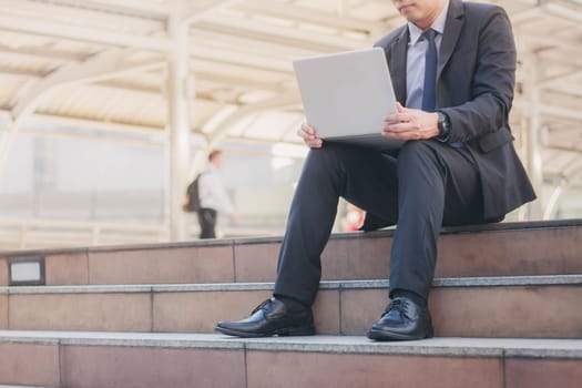 Business man is using a laptop working in the city.