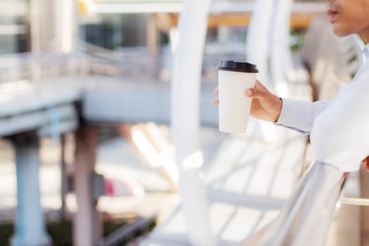 Man holding cup of coffee in city.