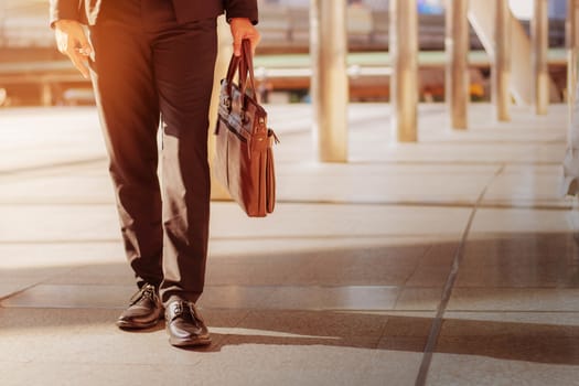 Young man walking carrying leather bag in the city.