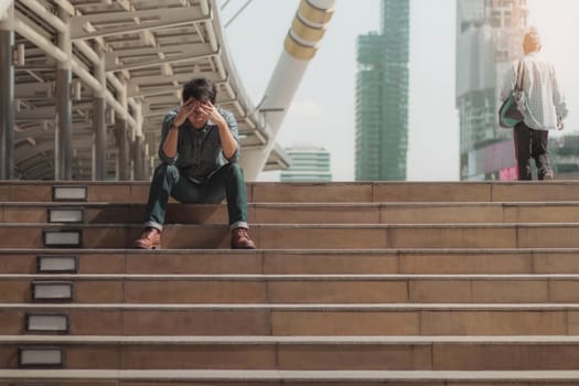 Man with failure sitting on stairway at sunlight.