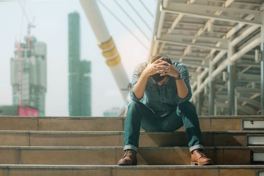 Young man with failure sitting on stairway in the city.