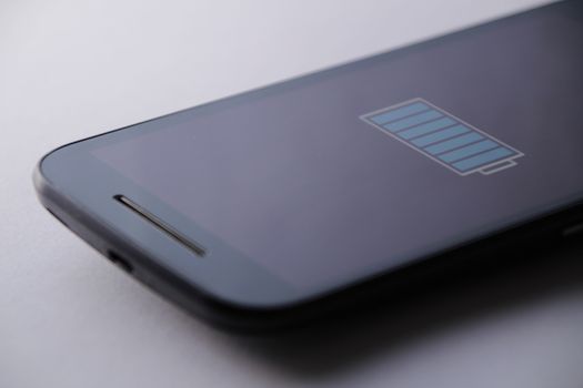 Smartphone charging battery with micro usb cable. White background.