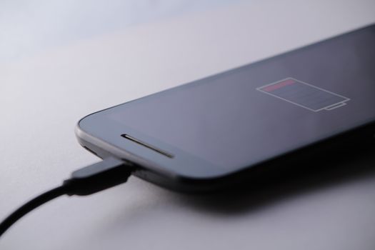 Smartphone charging battery with micro usb cable. White background.