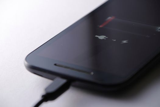 Smartphone charging battery with micro usb cable. White background.