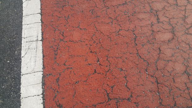 Red colored damaged road or paved pathway with crackes of different shpaes. Cracked texture with copy space for text and messages