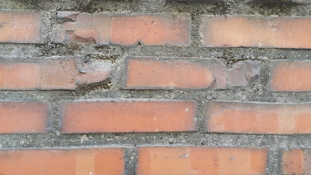 Closeup texture of red brick wall. A background of a weathered old exterior brick wall in the sunshine.